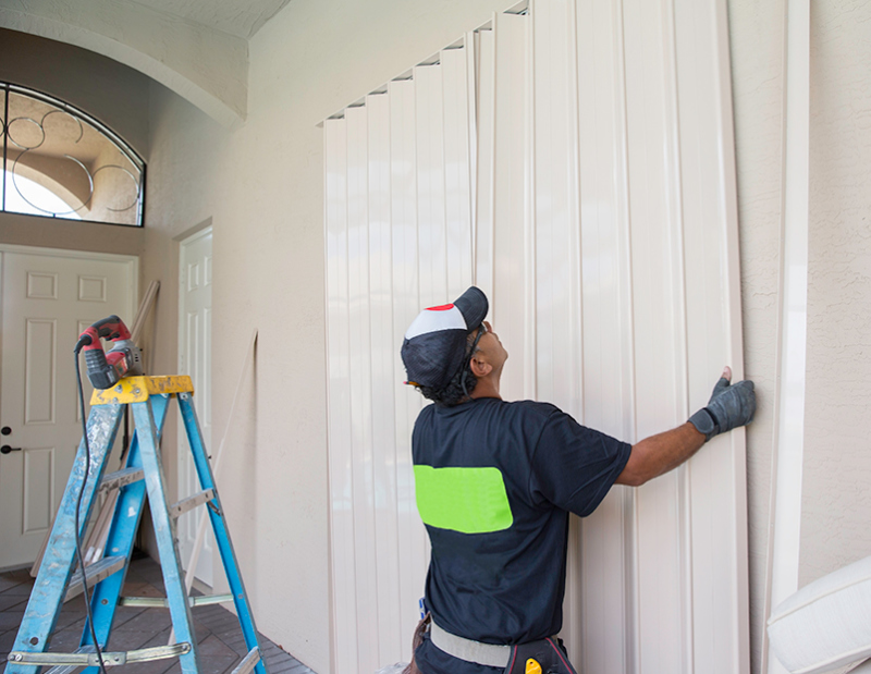 Man installing hurricane shutters in preparation for hurricane season