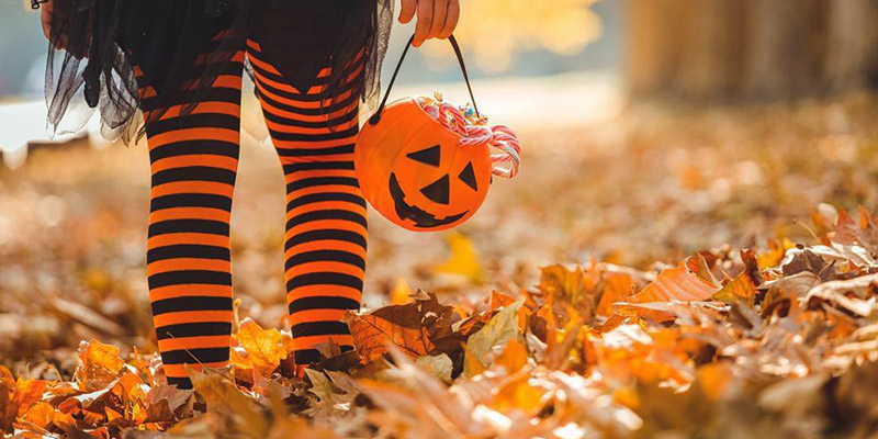 A photo of a child with a halloween treat-or-treat basket.