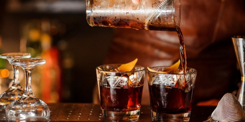 Bartender pouring cocktails into glasses at a restaurant bar, illustrating liquor liability risks and insurance coverage for food service businesses